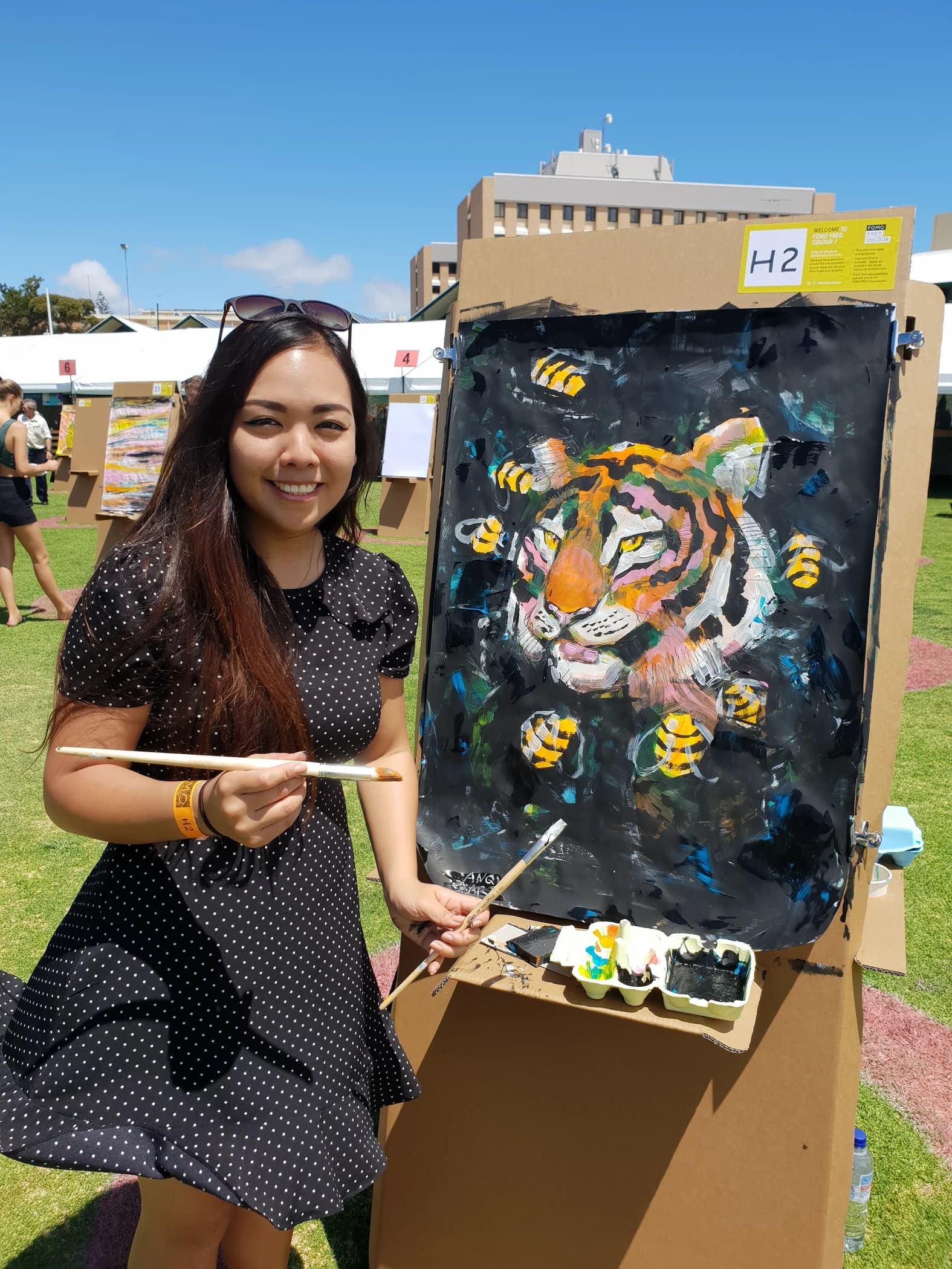 Angie smiling beside a tiger painting she made