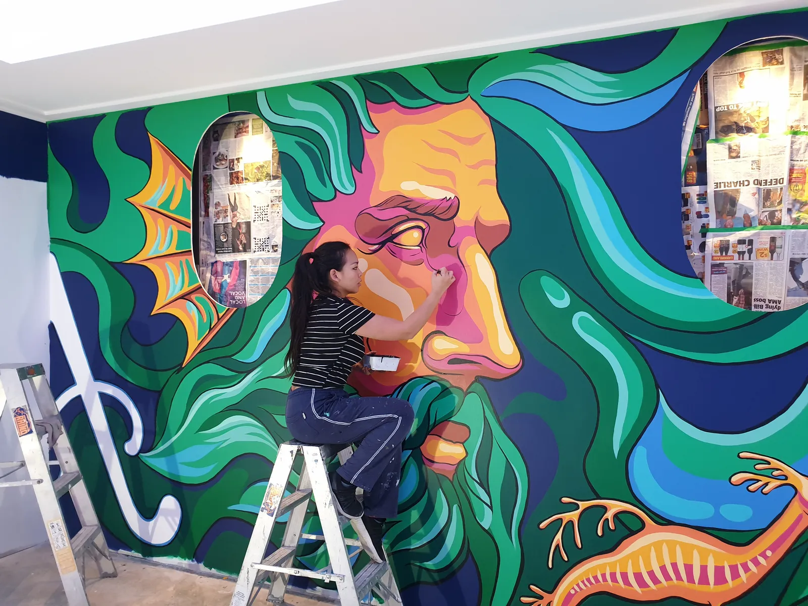 Anqi painting a large Neptune mural