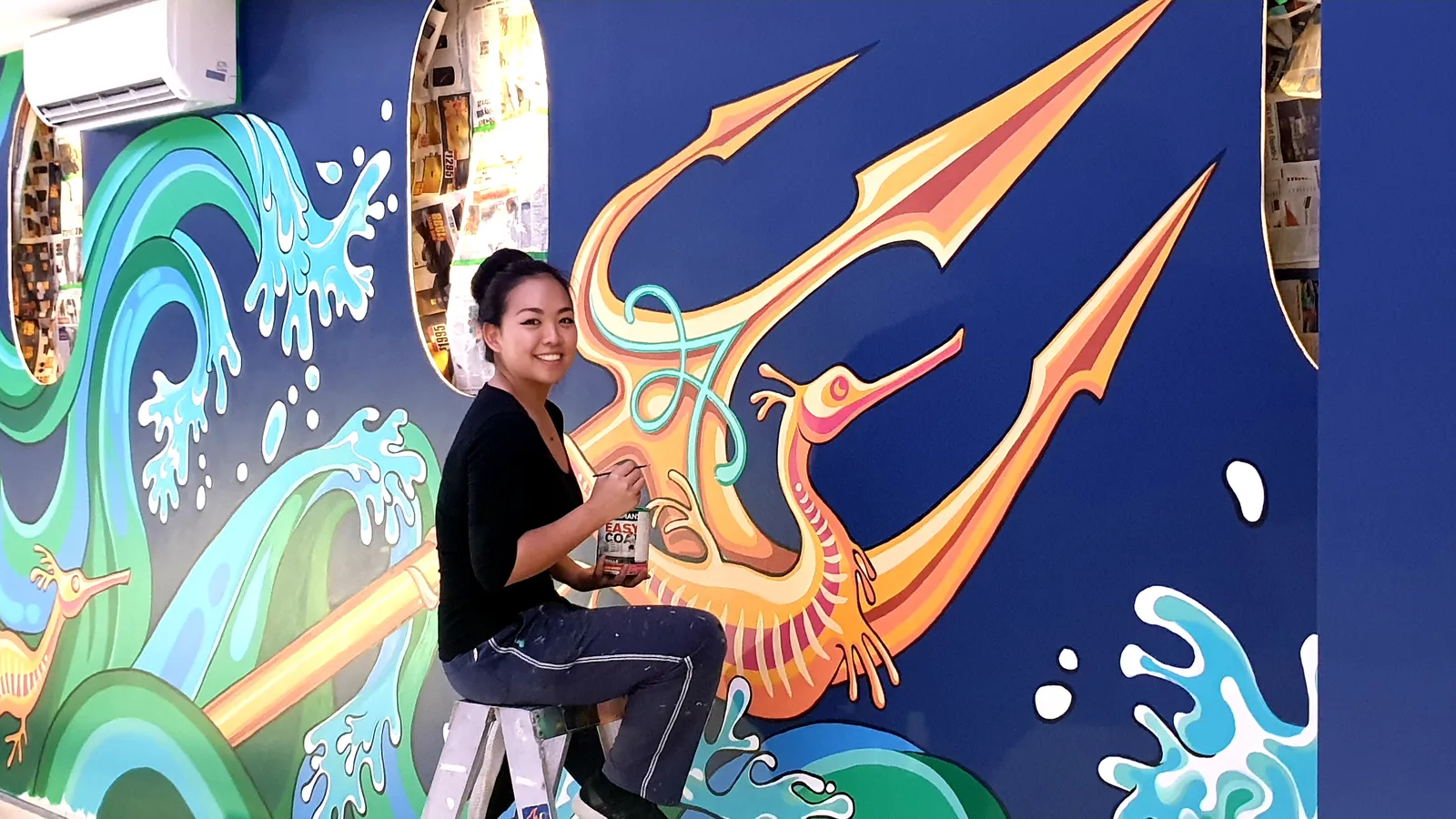 Anqi painting a trident mural